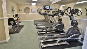 Et fitnesscenter med løbebånd, crosstrainere og en motionscykel.
