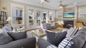A spacious living room with a fireplace, comfortable seating, and a television. - Whitesand - Gulf View, Heated Private Pool, Short Walk to the Beach! (Miramar Beach)