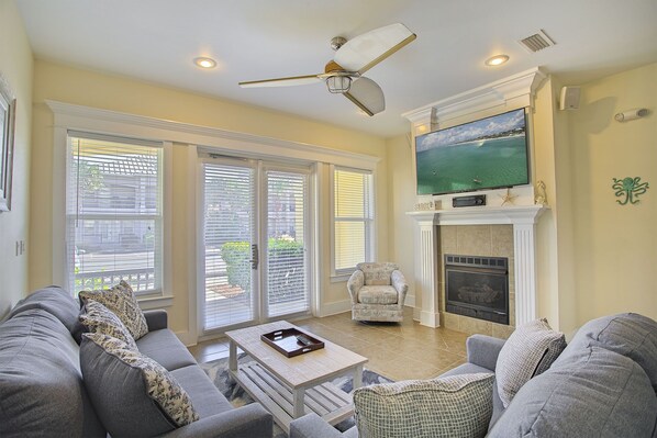 A living room with a fireplace, a television, and a ceiling fan.