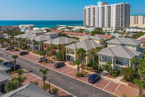 A residential area with multiple-story buildings, a parking lot, and a view of the ocean.