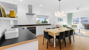 A modern kitchen with a dining area, white cabinetry, and a view of the city. - Averitts Favorite - Newly Renovated, Gulf View, Tang-O-Mar Community! (Destin)