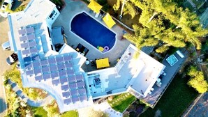 Oversigtsbillede af en ejendom med swimmingpool, solpaneler og anlagt have.
