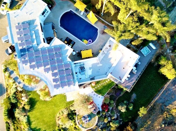 An aerial view of a property with a swimming pool, solar panels, and a landscaped garden.