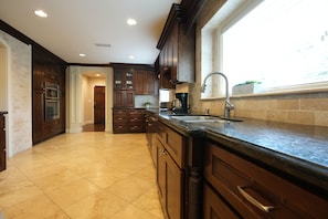 Enjoy cooking in this well-equipped kitchen with a large island and sink, offering a view of the outdoors.