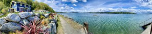 A lakeside property with a dock, a house, and a clear view of the lake. - SHABBY CHIC WATERFRONT RETREAT serene low bank waterfront home w/ gas fire pit. (Vashon)