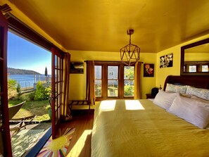 A bedroom with a large bed, a view of the sea, and a hammock outside. - SHABBY CHIC WATERFRONT RETREAT serene low bank waterfront home w/ gas fire pit. (Vashon)
