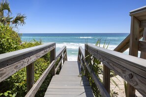 Pasarela de madera que conduce a una playa con vistas al océano.