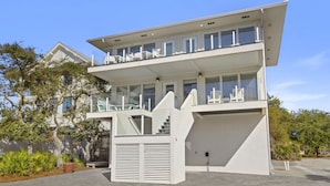A modern two-story building with a balcony on the upper floor, a garage door, and a staircase leading to the entrance. - Pelican Place - 30A, Seagrove Beach, Heated Saltwater Pool, Deeded Beach Access! (Santa Rosa Beach)
