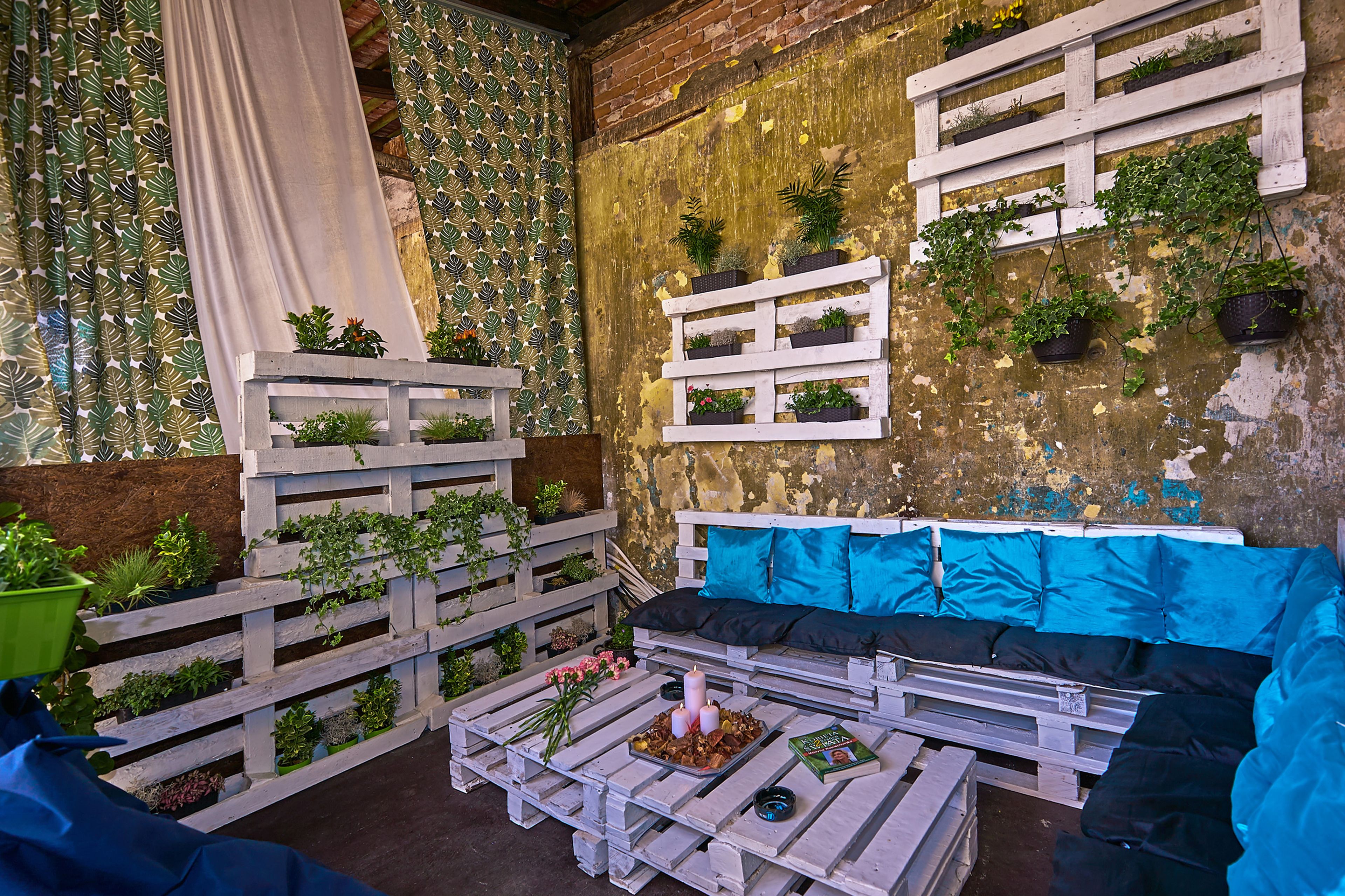 Un área de estar al aire libre acogedora, con un banco de madera rústico, un sofá con cojines y una mesa de comedor decorada con velas y flores.