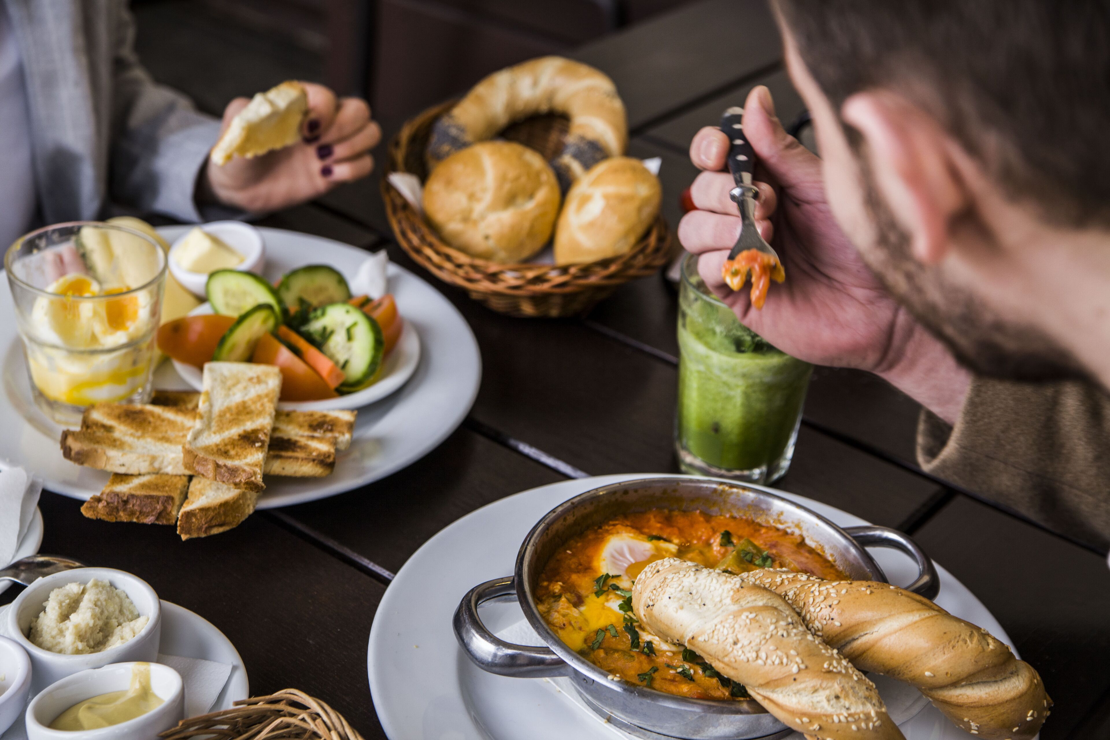 A dining table with a bowl of soup, bread, and various side dishes.