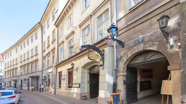 A historic building with a classic facade, a prominent arched entrance, and a sign indicating it is a hotel. - Draggo House- Hostel (Kraków)