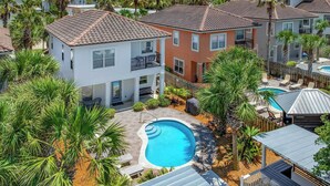 A residential area with a swimming pool surrounded by palm trees and a wooden deck. - Treasure Chest – Stylish Update, Heated Pool, No Roads to Beach + Outdoor Bar! (Miramar Beach)