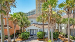 A residential area with a central building surrounded by palm trees and a paved walkway. - Treasure Chest – Stylish Update, Heated Pool, No Roads to Beach + Outdoor Bar! (Miramar Beach)