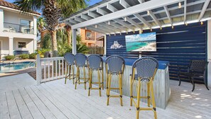 A poolside bar area with outdoor seating and a view of the ocean. - Treasure Chest – Stylish Update, Heated Pool, No Roads to Beach + Outdoor Bar! (Miramar Beach)