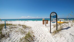 A beach with a signboard, white sand, and the ocean.