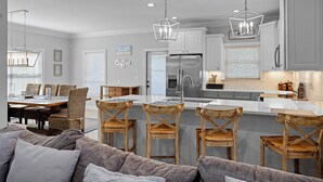 Una cocina moderna con una isla central, taburetes de bar y una zona de comedor con mesa y sillas.