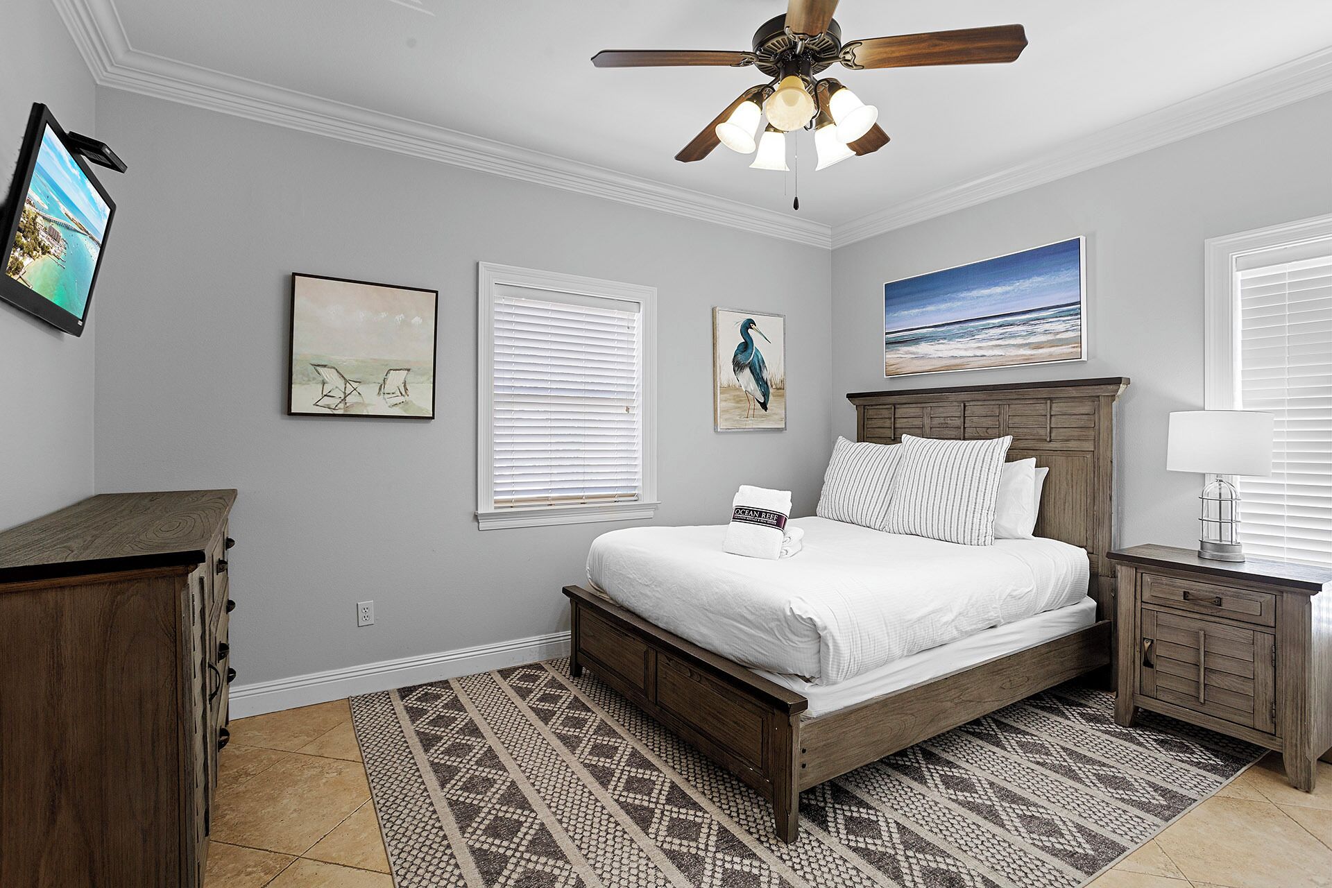 A bedroom with a wooden bed, a nightstand, a ceiling fan, and artwork on the walls.