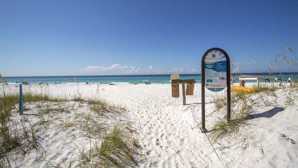 Una playa con un cartel, arena blanca y el océano.