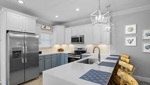 Una cocina moderna con armarios blancos, electrodomésticos de acero inoxidable y una isla central con individuales de diseño azulado.
