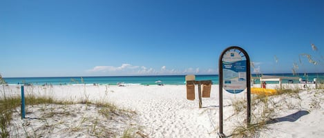 A beach with a signboard, white sand, and the ocean.