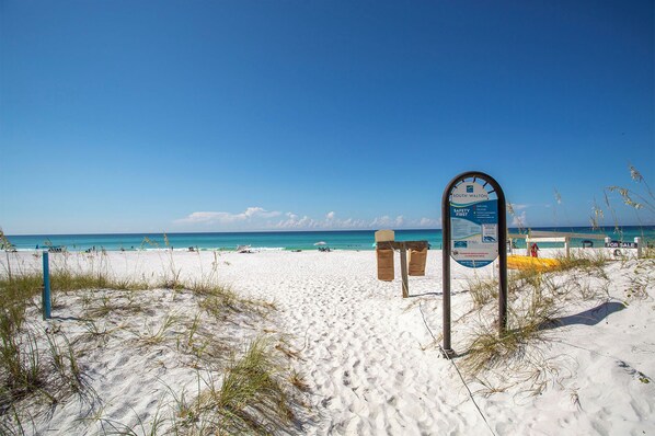 A beach with a signboard, white sand, and the ocean.