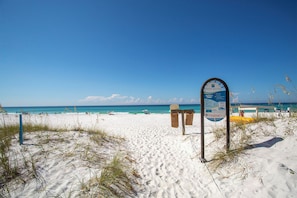 A beach with a signboard, white sand, and the ocean. - Surfin Safari - Heated Private Pool, Custom Tiki Bar, Steps to the Beach! (Miramar Beach)