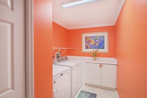 A laundry room with a washing machine, dryer, and a framed picture on the wall. - Amalfi Coast 201A - Miramar Beach! Gulf Views! Two Pools! Gym! Tennis Courts! (Miramar Beach)