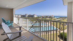 En balkon med udsigt til swimmingpool og hav.