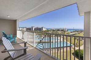 A balcony with a view of a swimming pool and ocean.