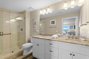 Une salle de bain moderne avec une douche à parois de verre, des toilettes blanches et un meuble-lavabo doté d’un grand miroir.