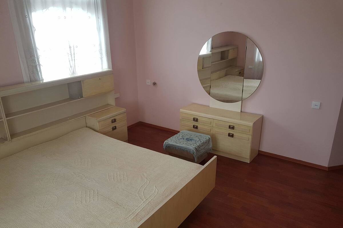 A bedroom with a bed, a dresser, a mirror, and a window.