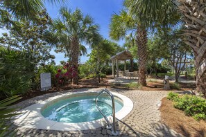 A hot tub surrounded by palm trees and a gazebo.