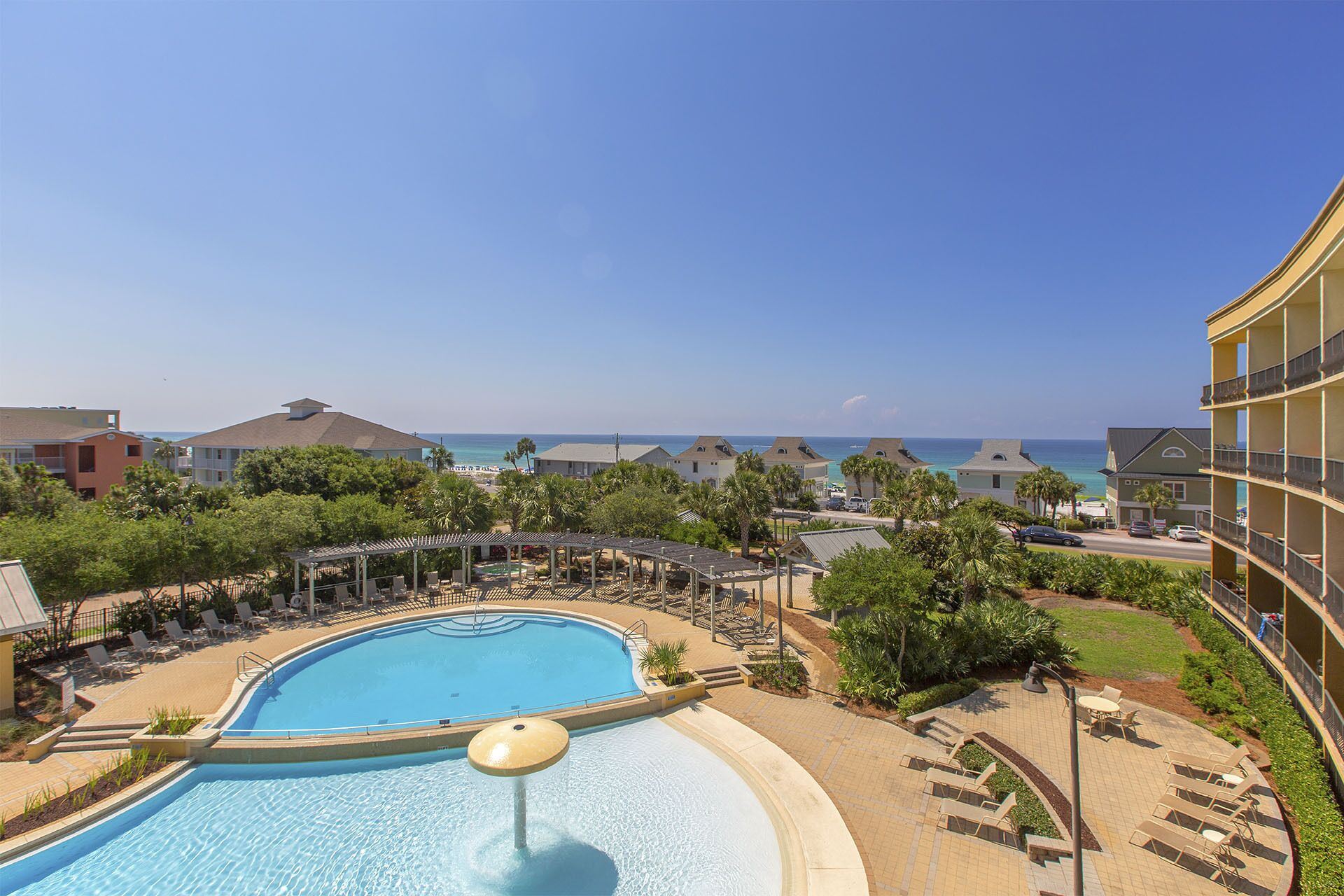 A resort with a swimming pool, lounge chairs, and a view of the ocean.