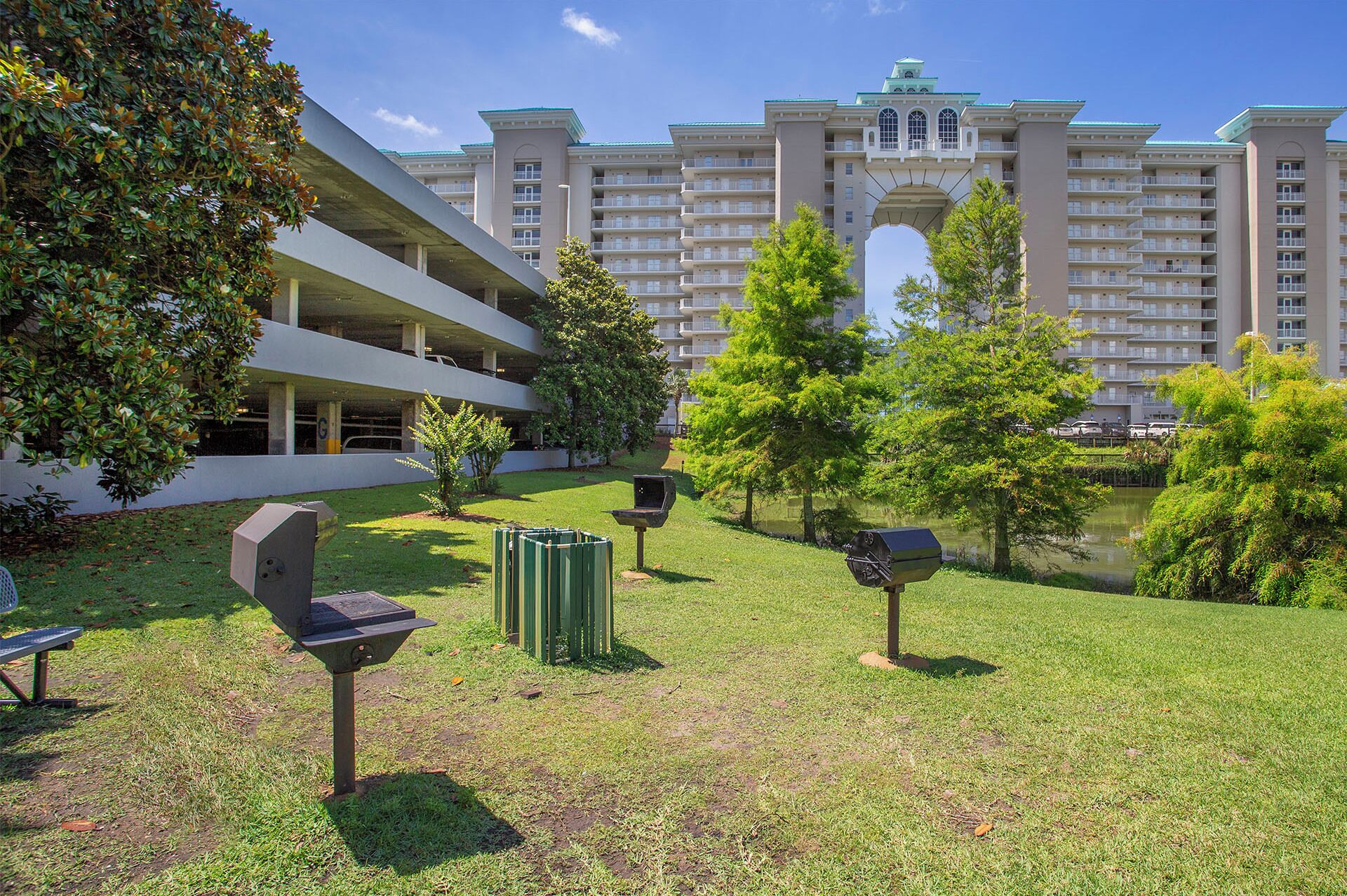 A hotel courtyard with a pool, outdoor seating, and a large building in the background.