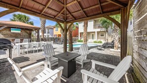 A covered outdoor patio with a grill, white Adirondack chairs, and a pool. - Breakaway (Updated) - Steps to the Beach! Private Pool! Great Outdoor Space! (Miramar Beach)