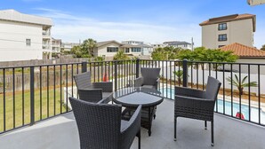 A balcony with wicker furniture and a view of a swimming pool and neighboring houses. - Panorama - Gulf Views! Heated Private and Community Pool! Free Beach Service! (Miramar Beach)
