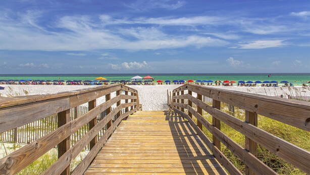 A wooden boardwalk leading to a beach with umbrellas and people. - Panorama - Gulf Views! Heated Private and Community Pool! Free Beach Service! (Miramar Beach)