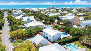 A coastal residential area with houses, a swimming pool, and a clear view of the ocean.
