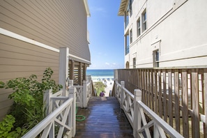 A wooden staircase leading to a beach, flanked by buildings with balconies.