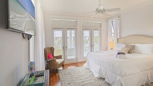 Een slaapkamer met een groot bed, een plafondventilator en een uitzicht door de deur.