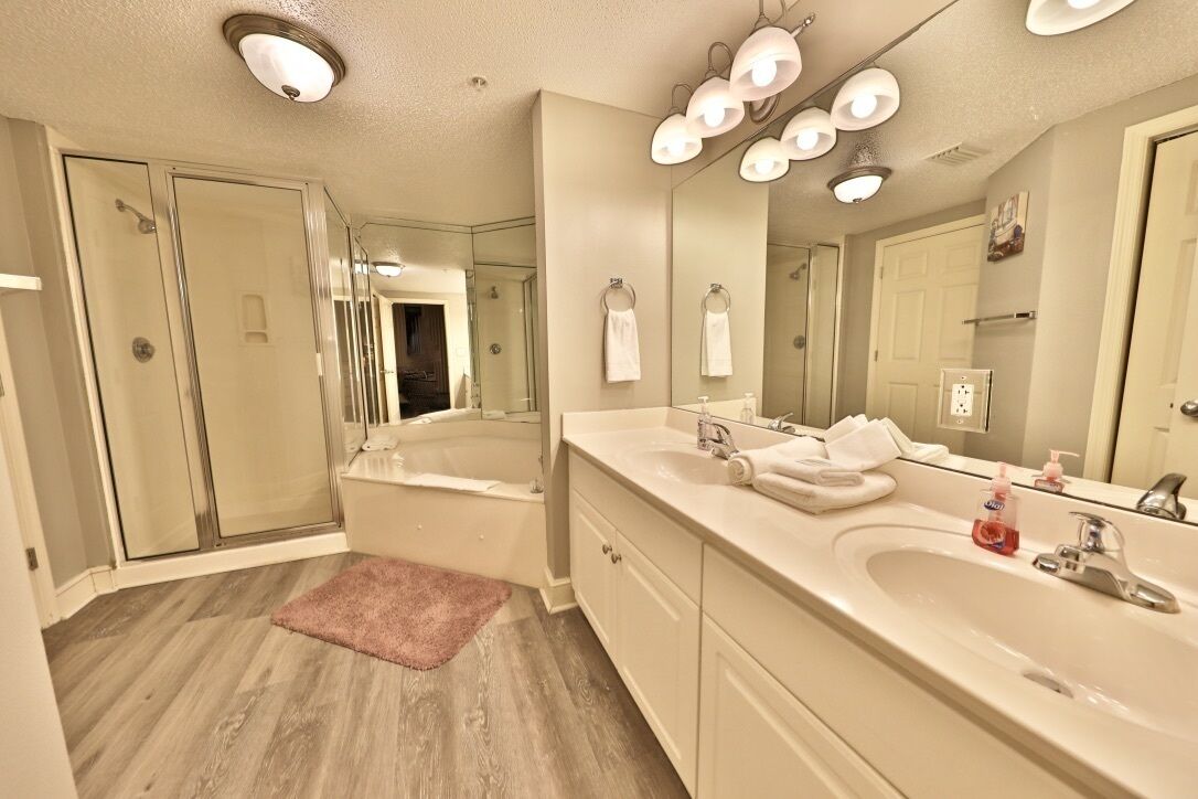 A modern bathroom with a large bathtub, two sinks, and a walk-in shower.