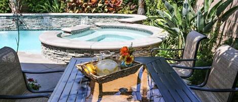 Zona de piscina con jacuzzi, mobiliario exterior y una mesa con bandeja para bebidas.