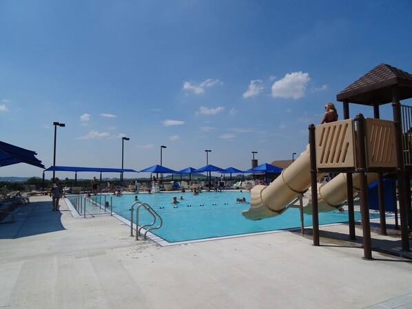 Relax by the pool surrounded by a shaded area, a children's slide, and a pavilion.