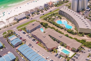 Vista aérea de un hotel costero con varias construcciones, una playa y una piscina.