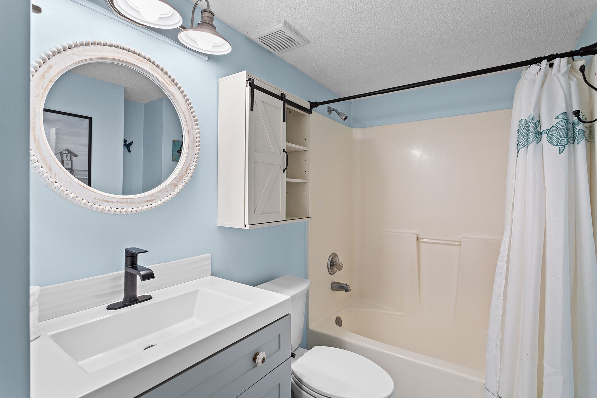 A bathroom with a white sink, a mirror, a toilet, and a shower area.