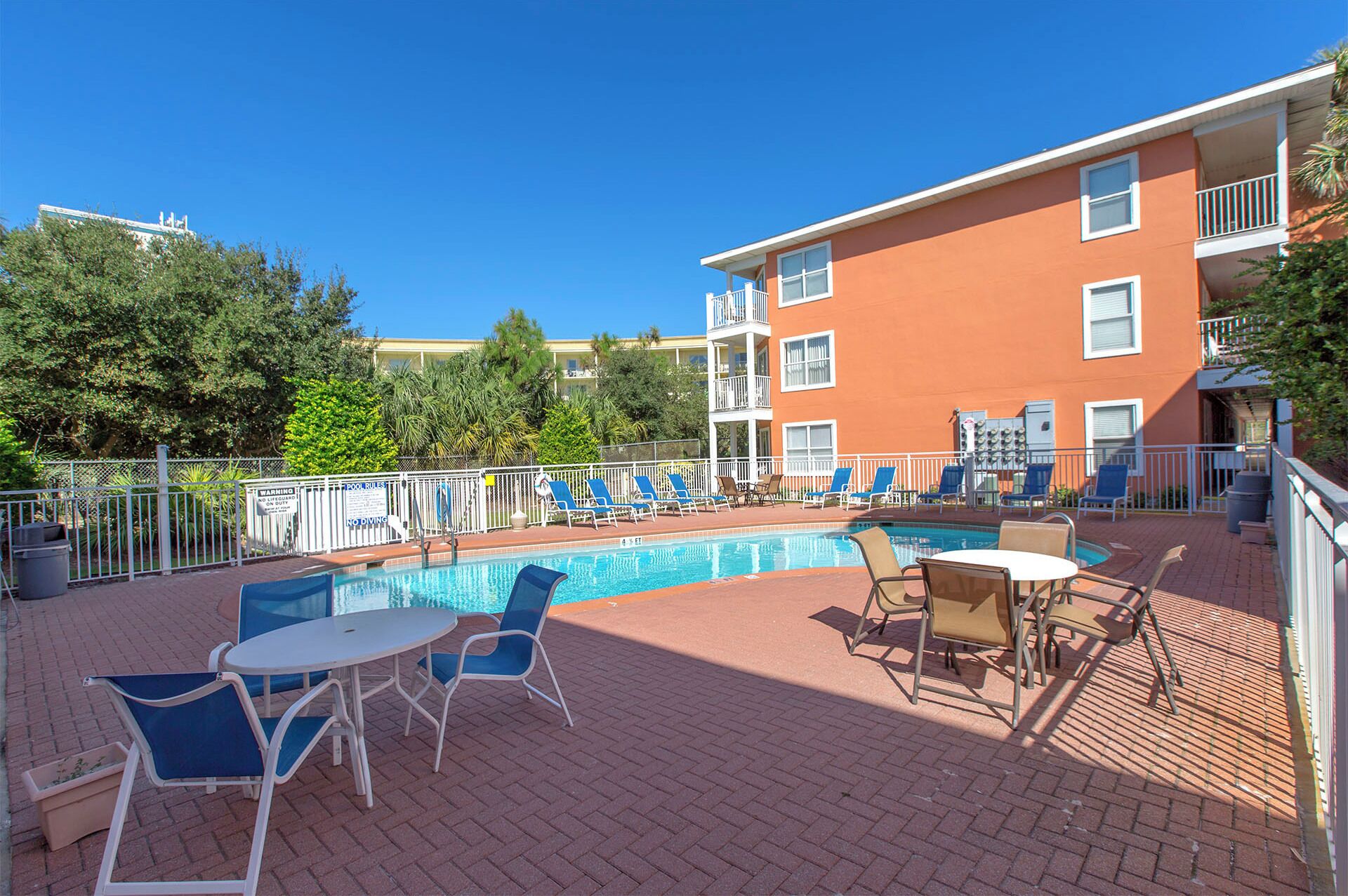 An outdoor swimming pool with lounge chairs and a table, surrounded by a brick patio.