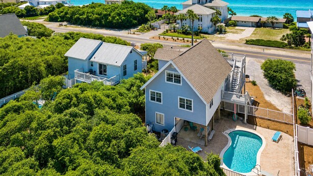 Um bairro residencial com uma casa que tem piscina, cercado por vegetação exuberante e vista para o oceano.