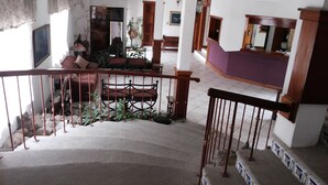 A spacious living area with a staircase, a ceiling fan, and a view of the upper floor. - Hotel Casa Flores De Tikal (Flores)
