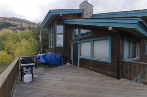 A wooden deck with a covered grill and a propane tank, overlooking a forested area. - High Country Hideaway (Steamboat Springs)