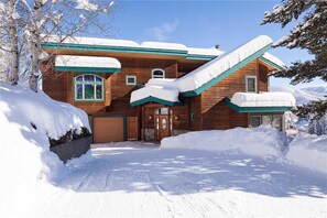 A wooden house with a snow-covered roof and a steep driveway. - High Country Hideaway (Steamboat Springs)
